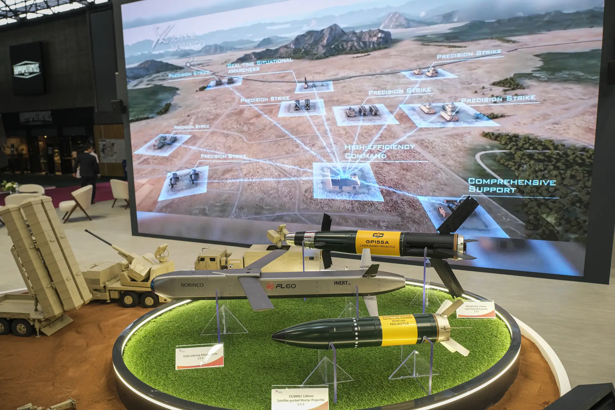 Missiles and guided shells displayed on artificial turf before a giant ’Precision Strike’ screen