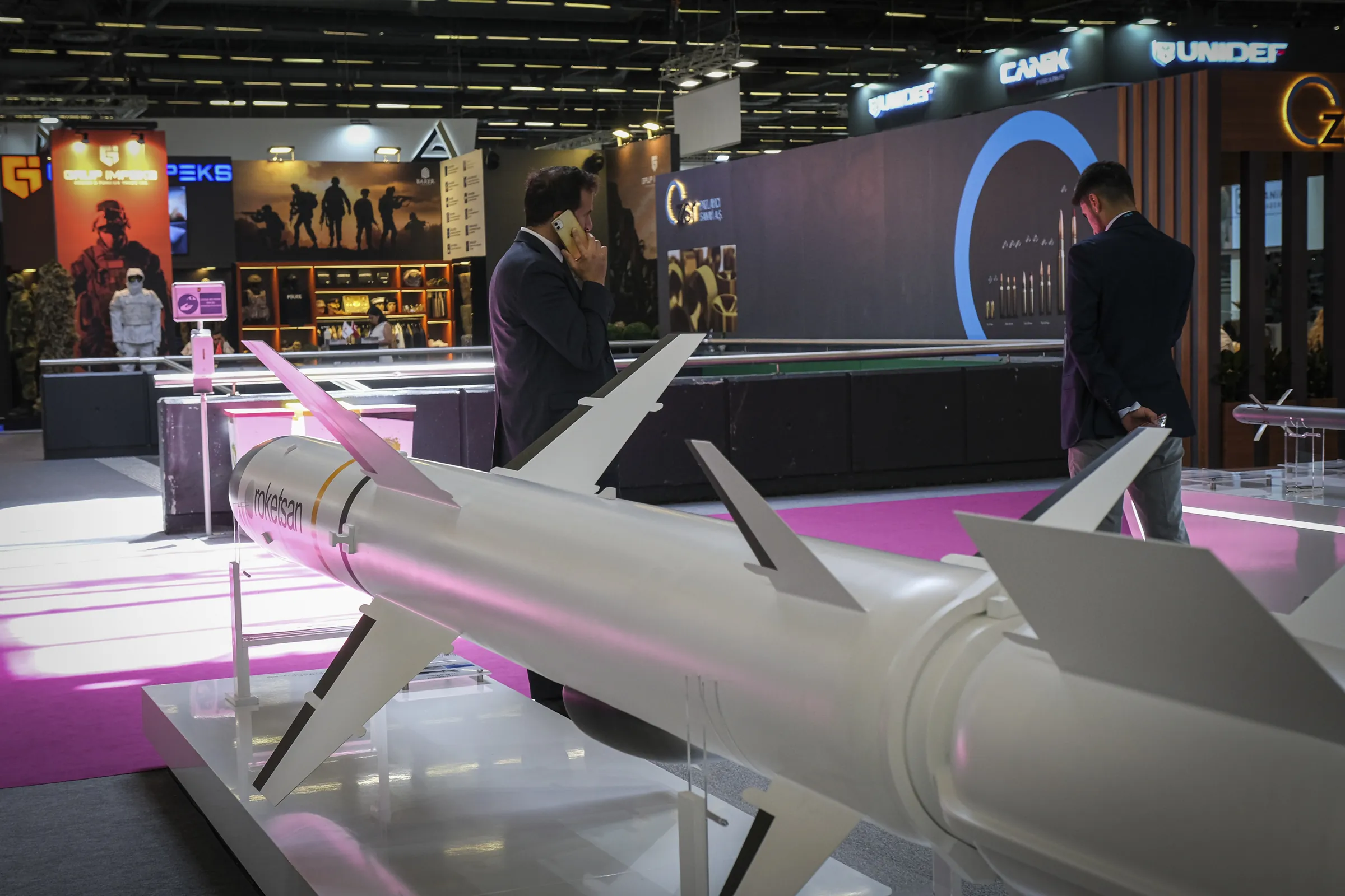 A white missile in the foreground of a pink-lit exhibition hall at Eurosatory 2022