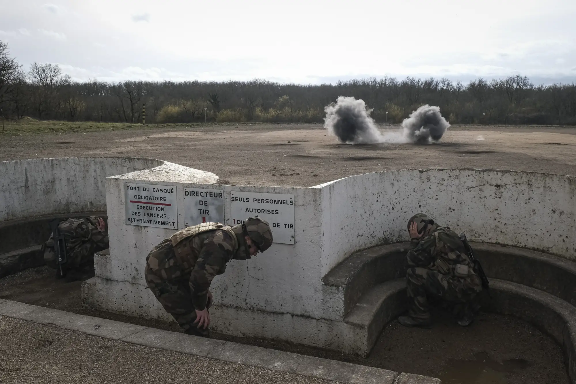 Recruits duck in concrete throwing pits as grenades explode downrange