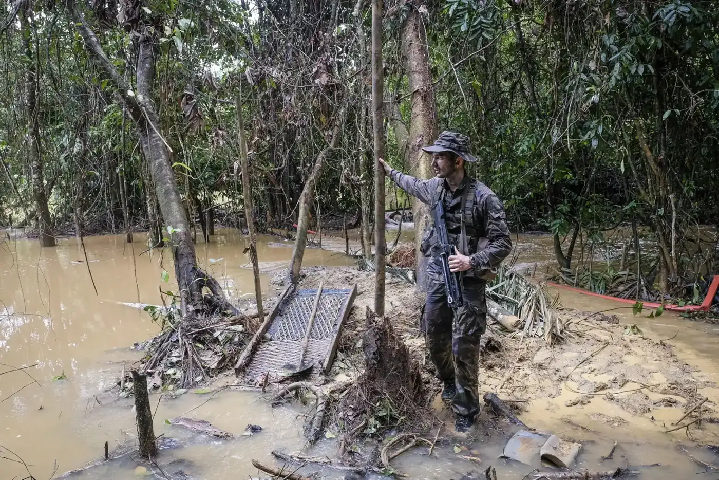 A French soldier stands over a dismantled sluice ramp at a flooded illegal gold-mining site