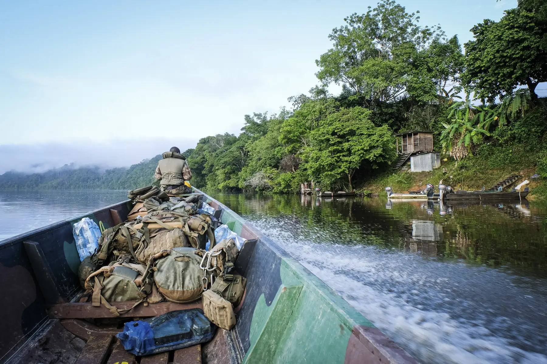 View from a gear-laden pirogue speeding on the Maroni river at misty morning, French Guiana