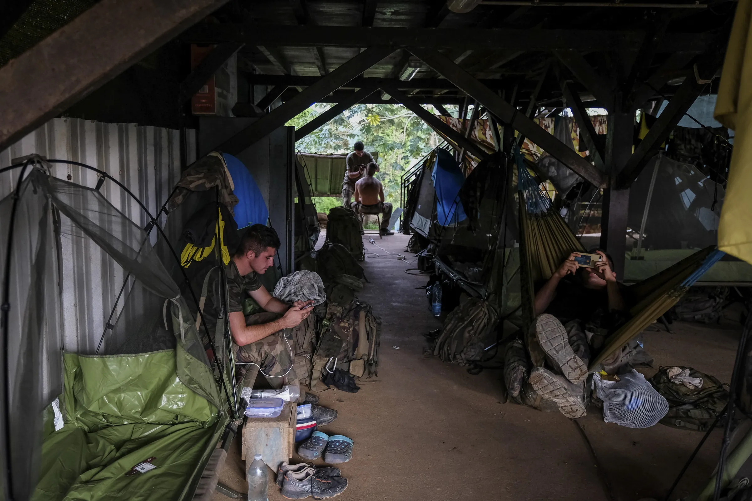 French soldiers rest among mosquito nets and hammocks in a jungle forward camp