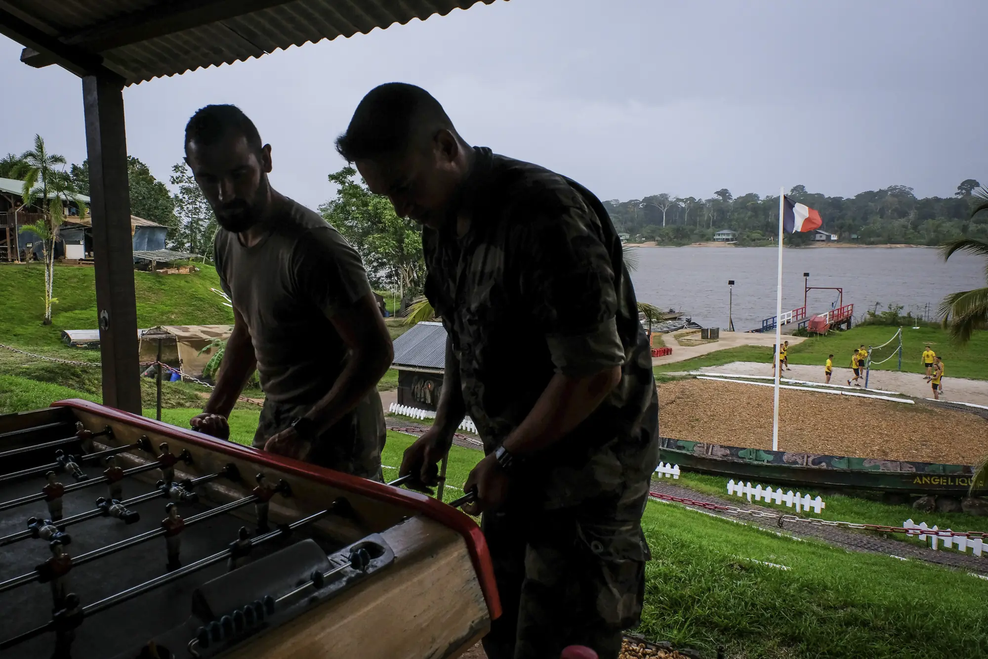French soldiers relax playing table football at the Maripasoula military camp, French flag above