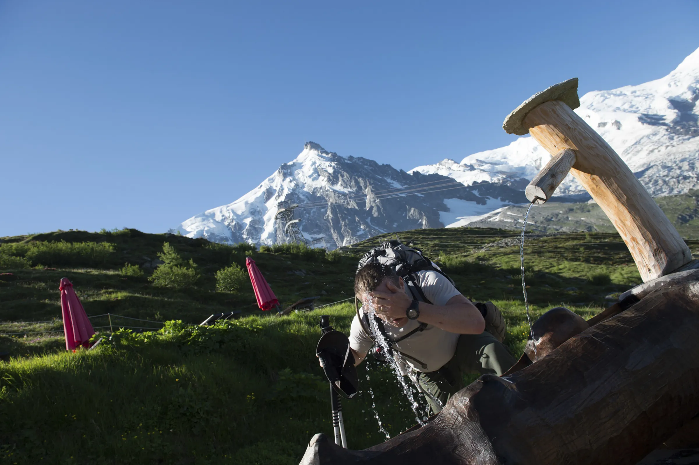 A soldier splashes his face at a fountain during a summer mountain race, the Aiguille du Midi behind