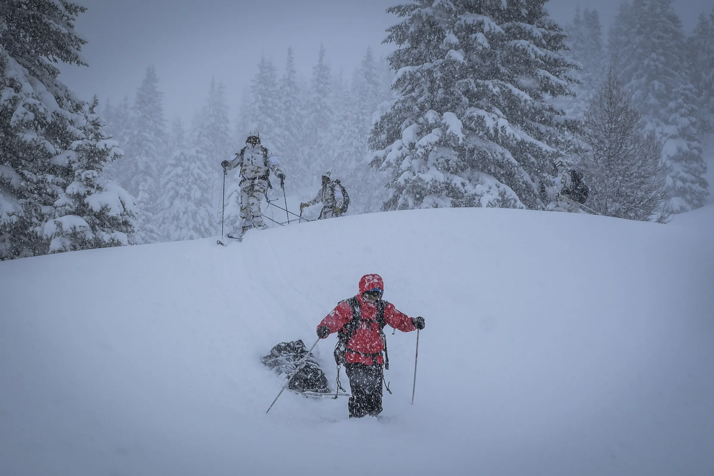 A GMHM instructor hauls a sled through thick falling snow, training commandos for polar environments