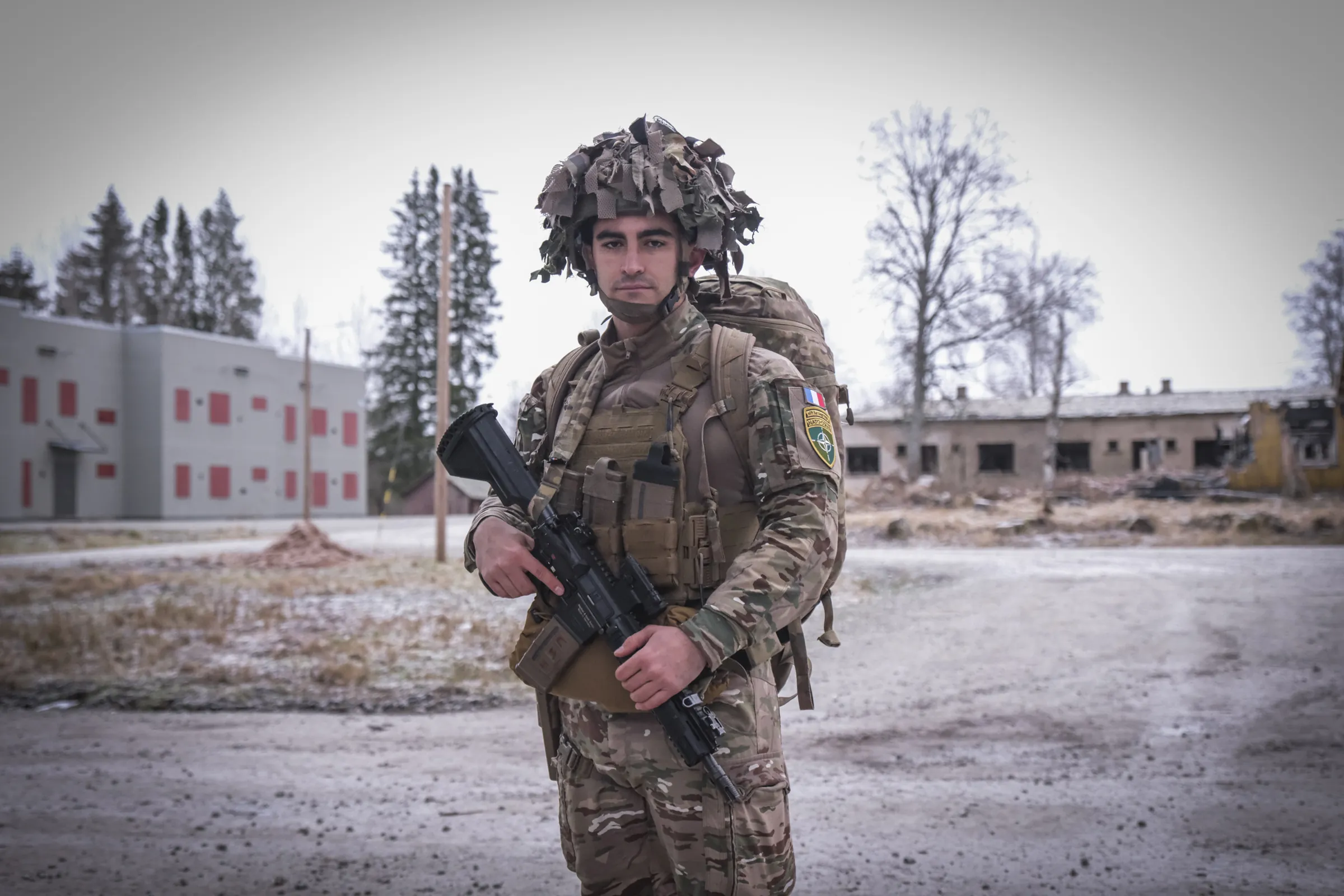 The commanding officer of the French detachment, rifle in hand, in a frost-dusted training village