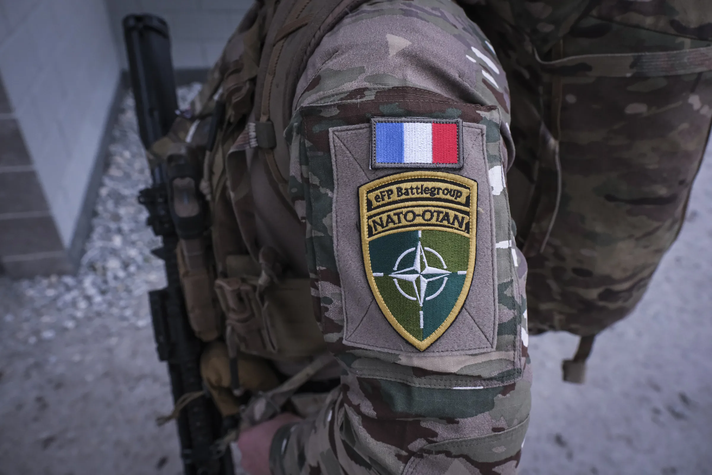 Close-up of a French flag above an eFP Battlegroup NATO shoulder patch on a soldier’s sleeve