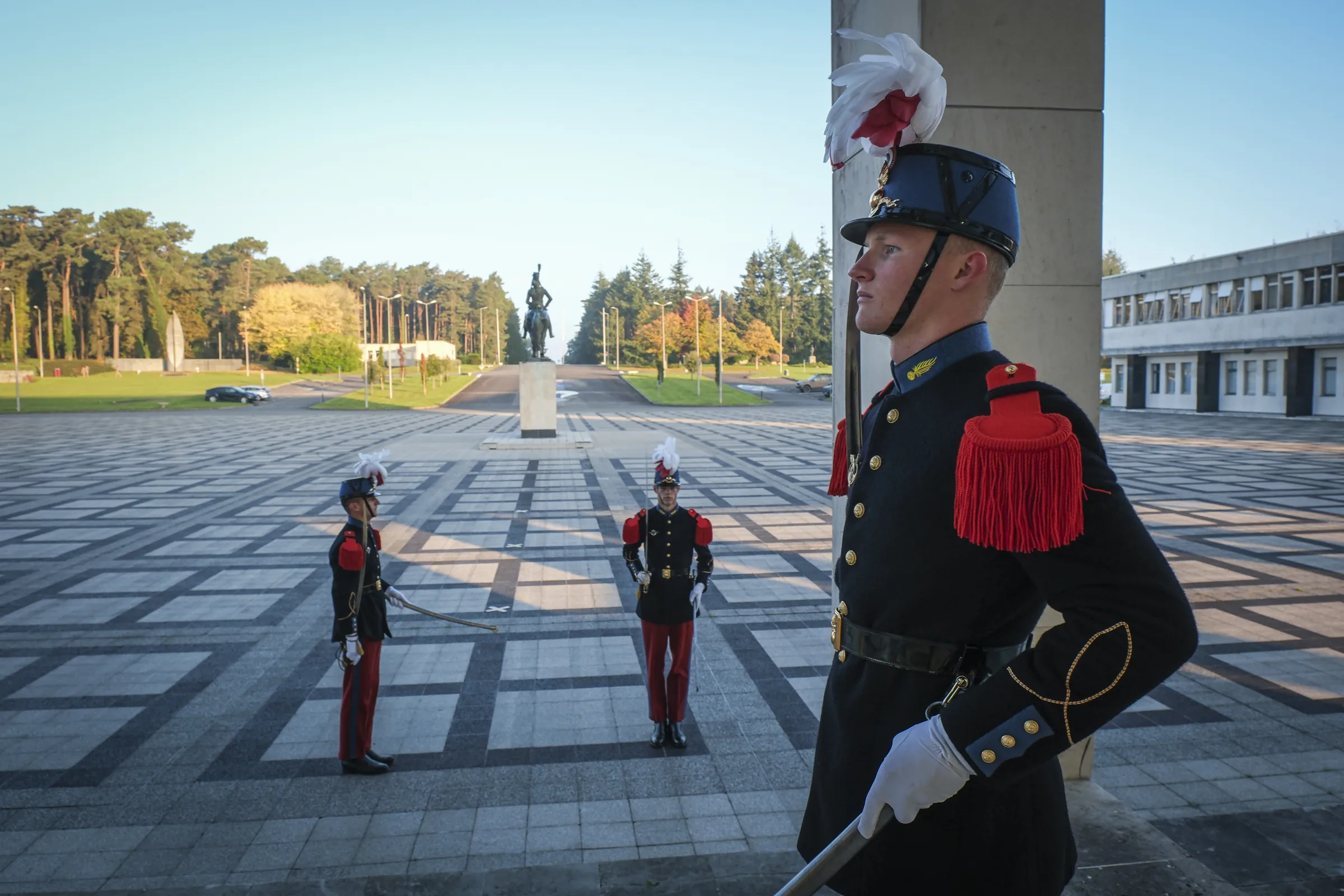 Three Saint-Cyr cadets in Grand Uniforme with plumed shakos stand guard on the parade square