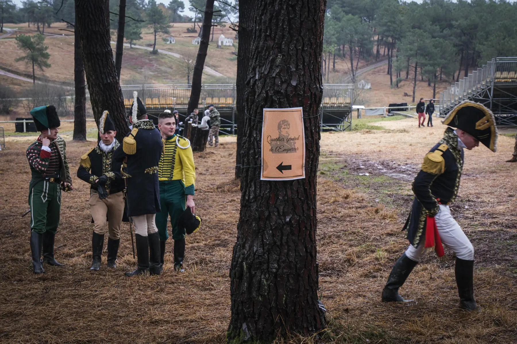 Cadets in Empire staff uniforms beside a pine bearing the sign ’Quartier général de l’Empereur’
