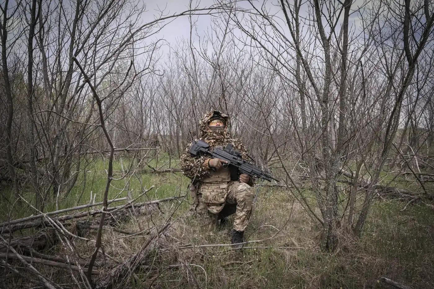 A machine-gunner of the Omega Unit’s special forces on patrol in the Donbass, almost invisible in the thicket