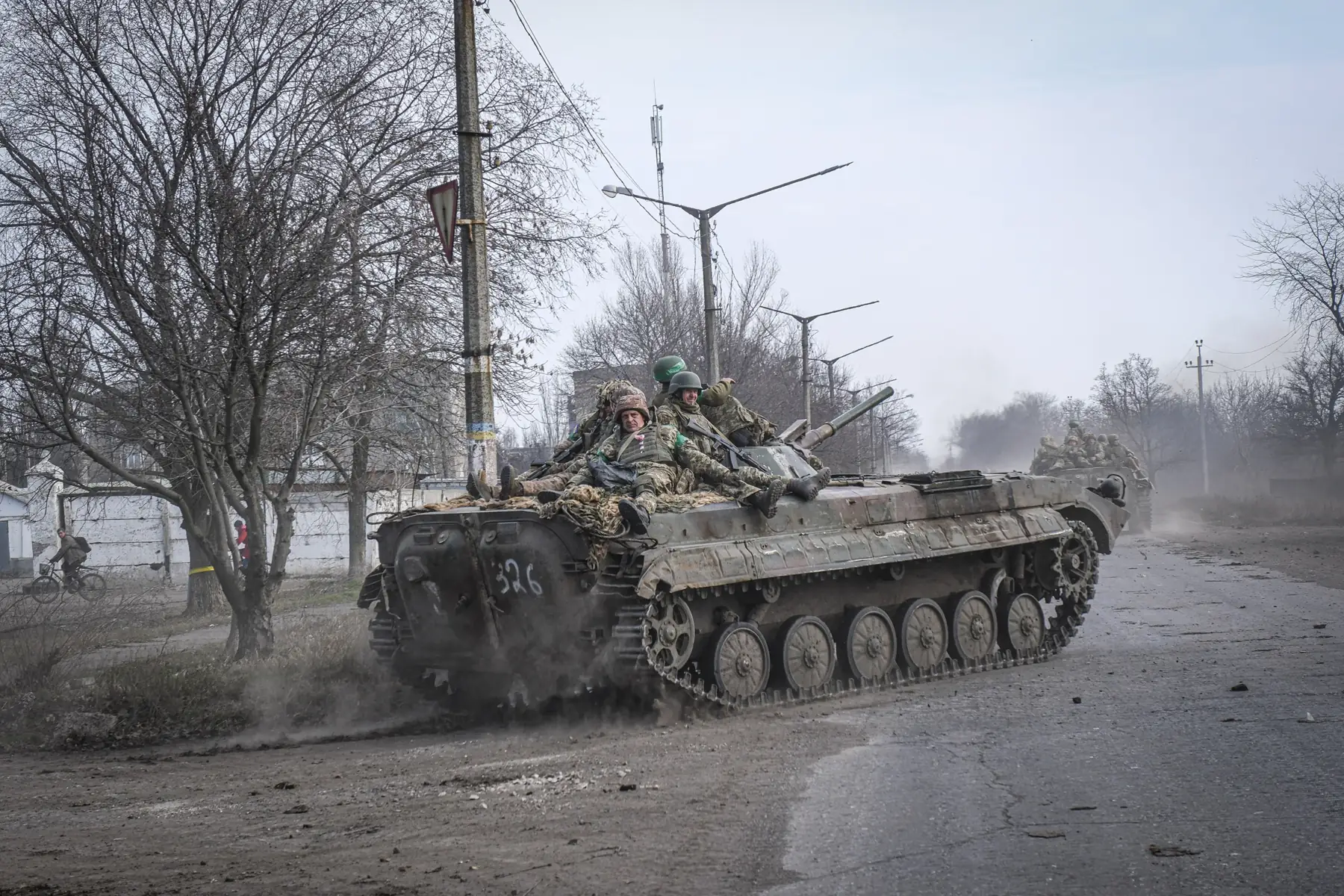 A BMP infantry fighting vehicle loaded with Ukrainian soldiers rolls through a shell-scarred town