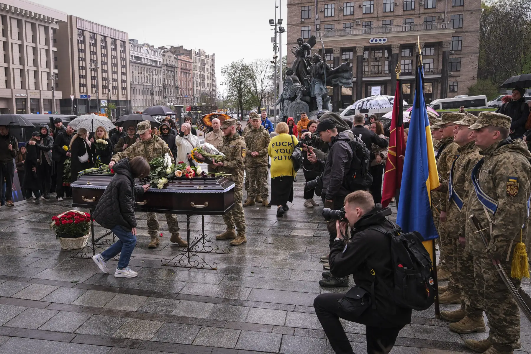 Military funeral of a Ukrainian soldier on the Maidan in Kyiv, honour guard and flowers in the rain